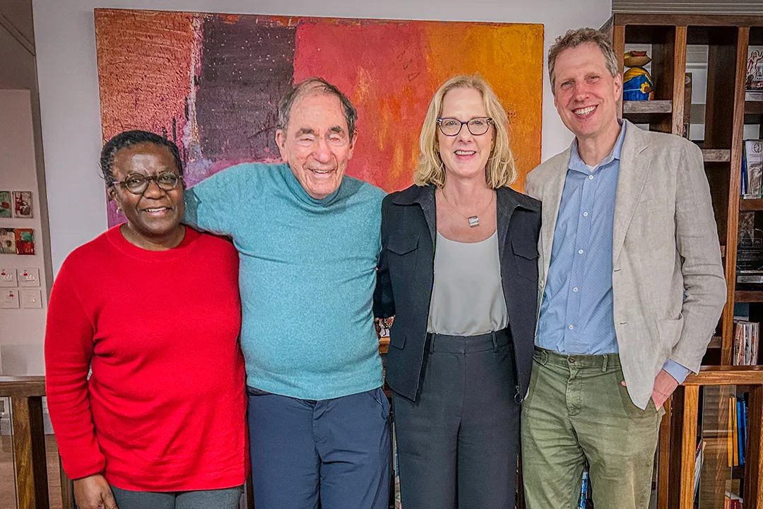 Four colleagues pose together smiling indoors in front of a colorful abstract painting, taken during a trip to South Africa.